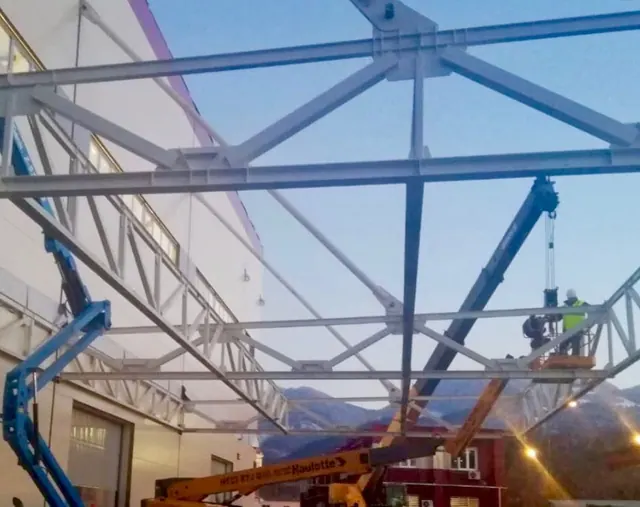Echipa montează o copertină metalică de pe o nacelă, la apus