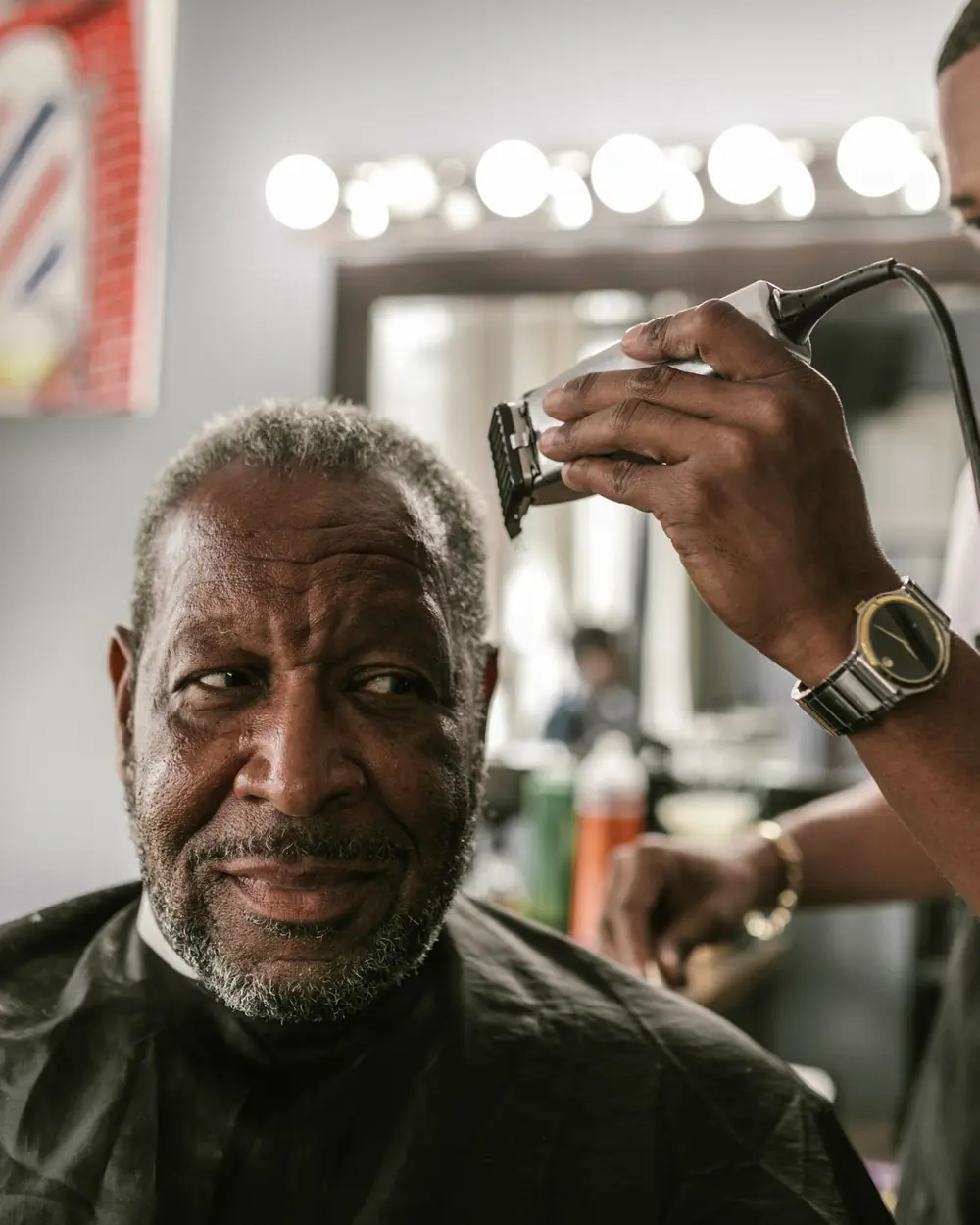 Barber trimming an older client's hair with clippers