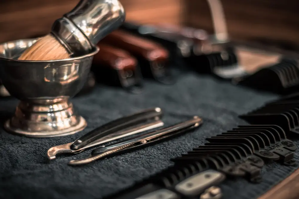 Straight razors, combs and a shaving brush laid out on a towel