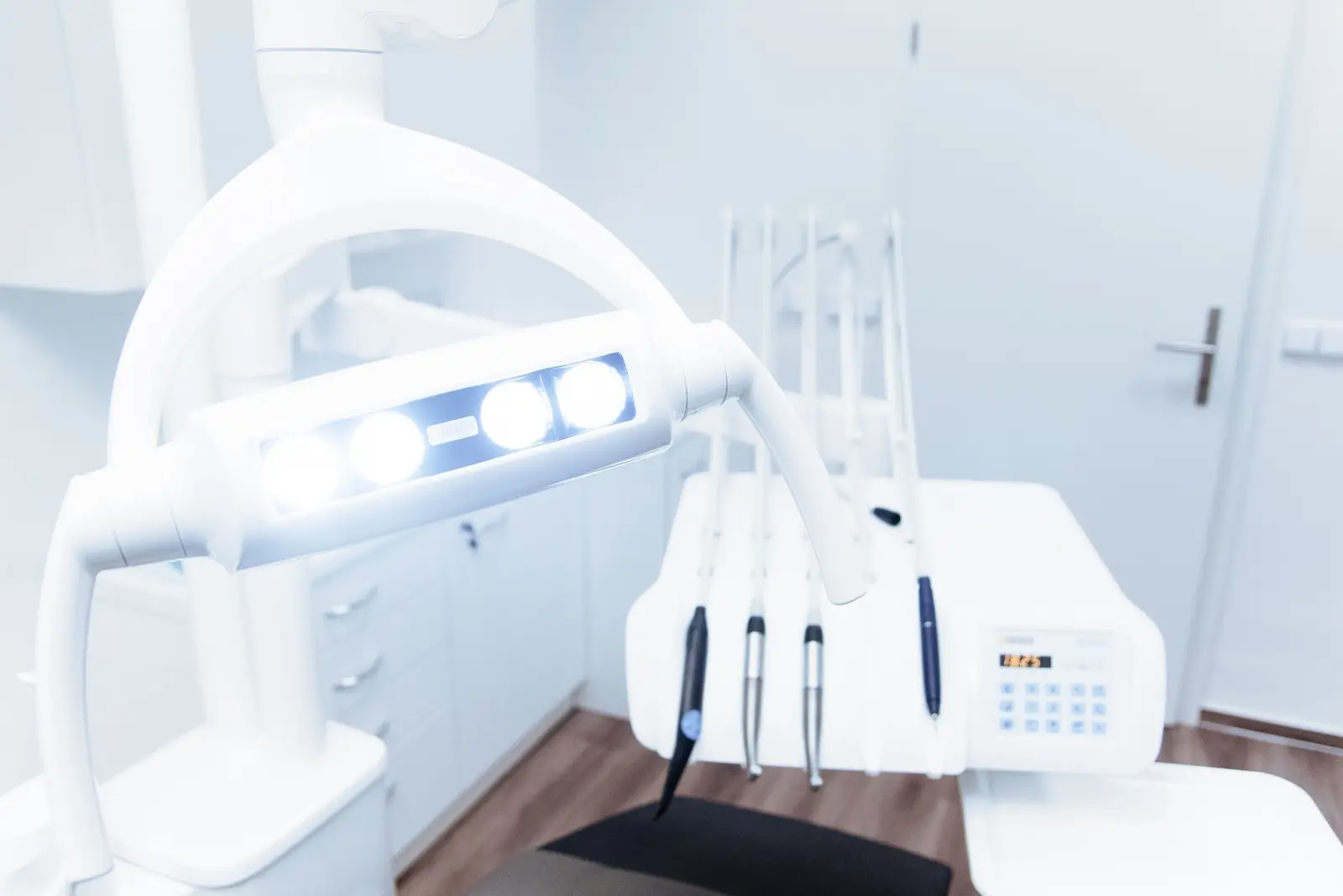Bright treatment room with a white dental chair and overhead lamp