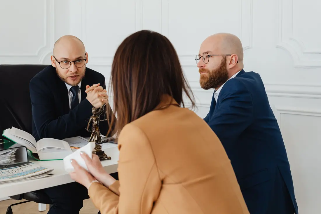Two lawyers talking a client through documents in a bright office