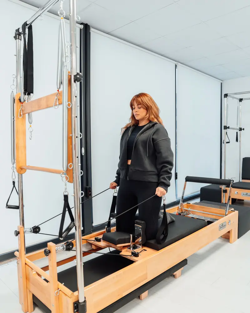 Instructor standing on a reformer with tower frame