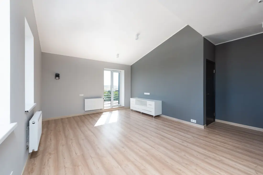 Finished empty apartment with pale wooden floors and a dark accent wall