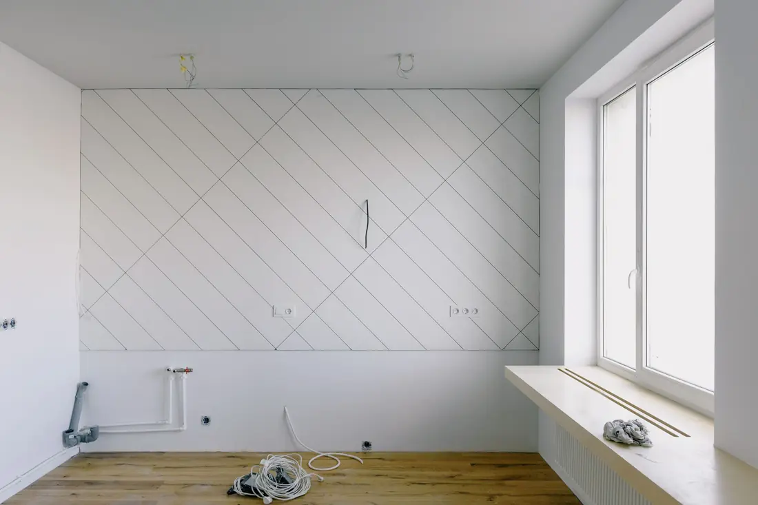 Kitchen with new wiring and pipes run along bare white walls