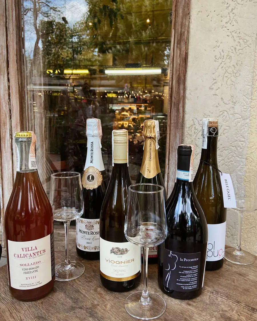 Several natural wine bottles and glasses on a wooden table